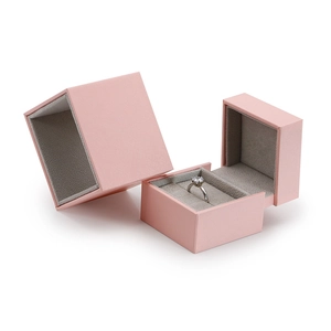 Pink textured square jewelry box with grey velvet lining and a proposal ring inside