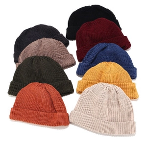 Detalle de gorros docker de punto apilados en varios colores como negro y burdeos