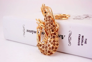 Macro detail of gold metal lobster keychain featuring sparkling champagne rhinestones