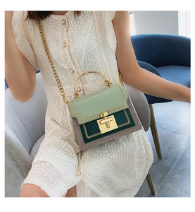 Detail of green patchwork handbag with gold metal handle and chain strap on a model