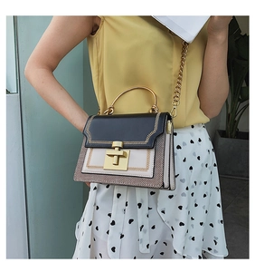 Detail of elegant two-tone crossbody bag with golden hardware and V-shaped stitching