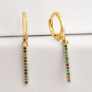 Detailed close-up of gold drop earrings with multi-colored crystals on white steps