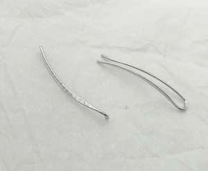 Detailed close-up of silver U-shaped ear clip with hammered metal texture on white background