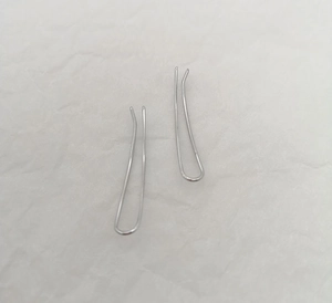 Detailed view of silver U-shaped curve earrings with a minimalist hammered metal texture