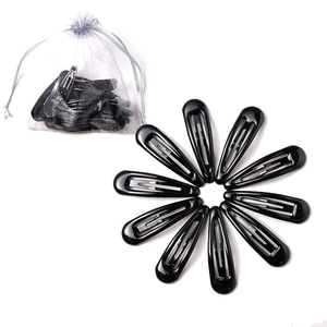 Macro view of black metal snap hair clips arranged in a circle with a white mesh bag