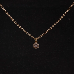 Macro shot of gold snowflake pendant necklace with sparkling cubic zirconia on black background