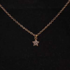 Macro shot of a gold necklace featuring a star pendant set with sparkling zircon stones