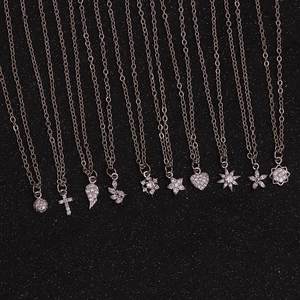 Detailed close-up of multiple silver pendant necklaces with zircon on black texture