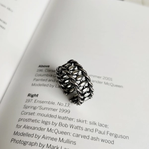 Close-up of vintage oxidized 925 silver open ring with braided texture on book background