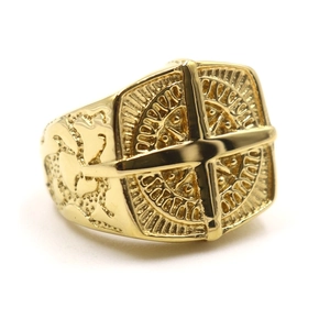 Macro detail of golden Freemason signet ring with engraved cross and sun compass emblem