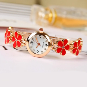 Women's gold quartz watch featuring red clover flower strap and white rhinestone dial