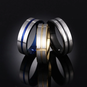 Detailed view of three stainless steel rings in blue, gold, and black with brushed finish