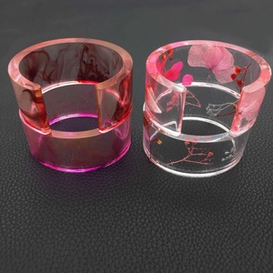 Macro detail of oval resin bangles featuring magenta gradient and embedded red dried flowers