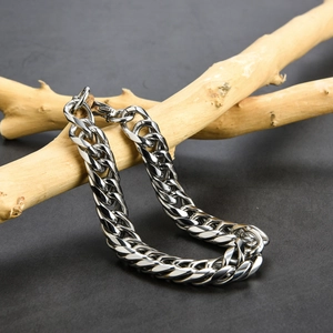 Detailed close-up of polished silver stainless steel Cuban link chain on a wooden stand