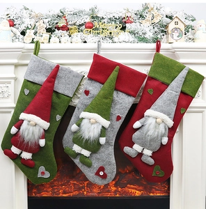 Vue détaillée de trois chaussettes de Noël en feutre avec motifs de gnomes sur une cheminée