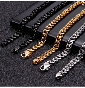 Dettaglio di bracciali a catena cubana in nero, oro e argento con chiusure a moschettone