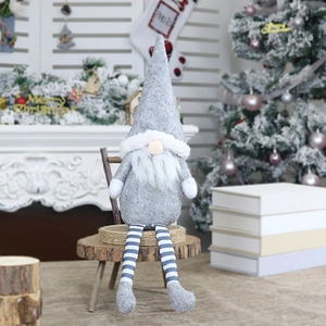 Gray long-legged Christmas gnome plush toy sitting on a stool in a festive home setting