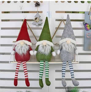 Detailed view of three long-legged Christmas gnomes in red, green and grey on a shelf