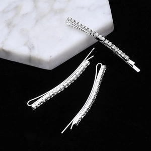 Close-up of three silver rhinestone hair clips with sparkling crystals on marble base