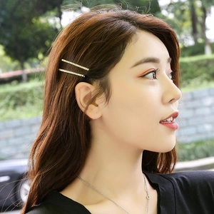 Golden rhinestone hair pins set on model's hair with a natural outdoor background