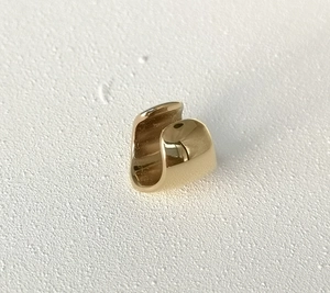 Detailed close-up of polished gold U-shaped ear cuff with smooth mirror finish texture