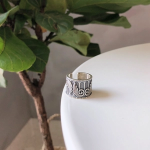 Macro shot of vintage silver open ring with intricate floral relief on a white surface