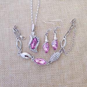 Detailed overhead shot of pink crystal angel jewelry set on a natural linen background