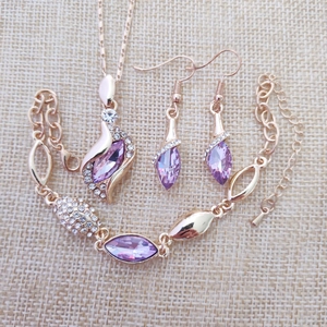 Flat lay of gold jewelry set with purple gemstones including necklace and earrings