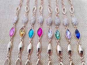 Detailed flat lay of gold crystal bracelets in pink, blue, yellow, and purple colors