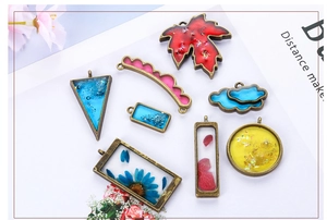 Detailed close-up of 8 assorted geometric resin pendant charms with dried flowers