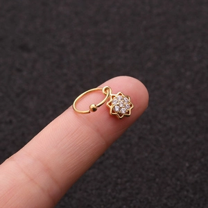 Primo piano di un piccolo orecchino a cerchio d'oro con ciondolo a stella sulle dita