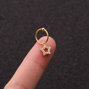 Dettaglio di un orecchino a cerchio dorato con un pendente a stella con zirconi lucenti