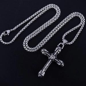 Detail view of a silver hip hop cross pendant with retro patterns on a black background