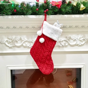 Gros plan d'une chaussette de Noël en tricot rouge avec fourrure blanche et pompons sur la cheminée