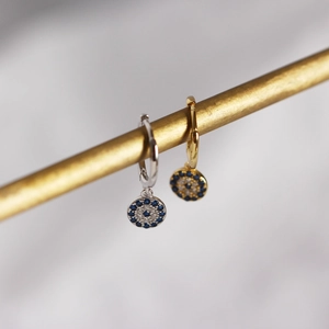 Macro detail of silver and gold S925 sterling silver devil eye hoop earrings with gems