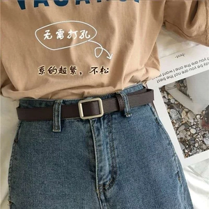 Close-up of slim brown leather belt with silver square buckle on blue denim jeans