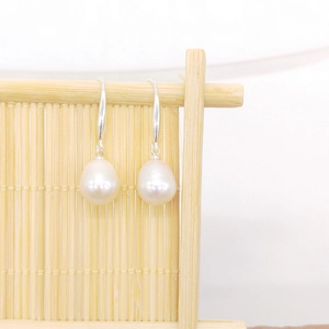 Close-up of teardrop freshwater pearl earrings on a natural bamboo display stand