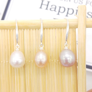 Three pairs of natural freshwater pearl earrings in white pink and purple colors on bamboo