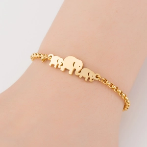 Detailed view of a gold elephant family pendant bracelet on a person's wrist