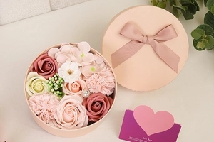 Close-up of a pink round soap flower gift box with roses, carnations and a heart card