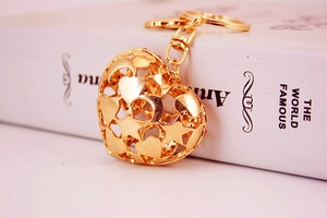 Detail of a gold heart keychain with rhinestone accents and cutout star patterns