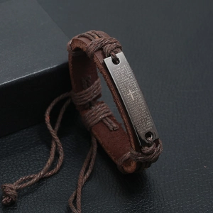 Brown braided leather bracelet with dark metal plate featuring the Spanish Lord's Prayer