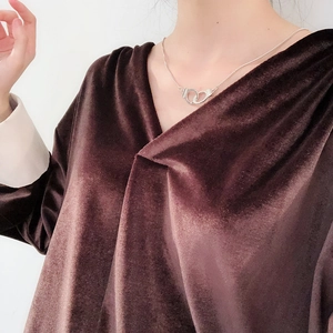 Close-up of vintage-style silver handcuff pendant necklace worn on a velvet top
