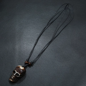 Handcrafted tribal skull pendant necklace with resin bone effect on black leather background