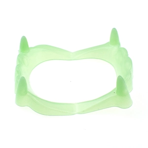 Close-up of green plastic vampire fangs toy for Halloween costumes on white background