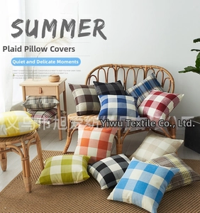 Detail showing various colorful plaid linen cushion covers stacked in a cozy home setting