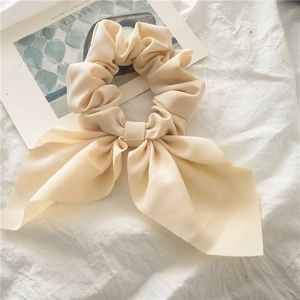Detail of soft apricot bow scrunchie with long ribbons on artistic Siesta background