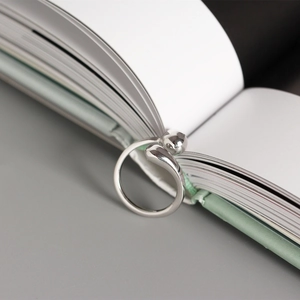 Detail of minimalist S925 sterling silver ring with water drop tips on open book