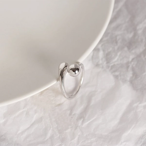 Minimalist S925 sterling silver ring with smooth round bead on a white ceramic plate