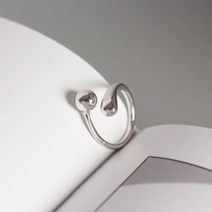Macro shot of polished silver open ring featuring a minimalist bead and teardrop design